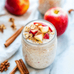 Apple cinnamon overnight oats in a glass jar styled with apples and cinnamon
