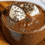 Bowl of high protein chocolate chia seed pudding topped with berries and nuts